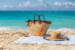Koszyk, okulary przeciwsłoneczne i olejek do opalania na plaży