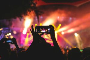 Koncert festiwalowy z kolorowymi światłami nagrywany smartfonem