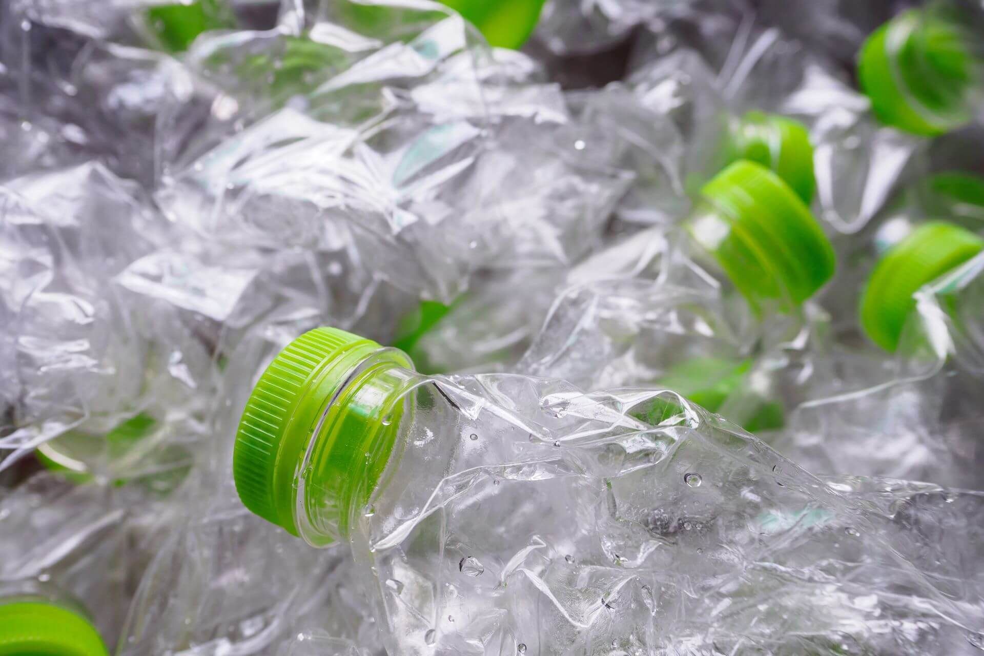 Zgniecione plastikowe butelki z zielonymi nakrętkami