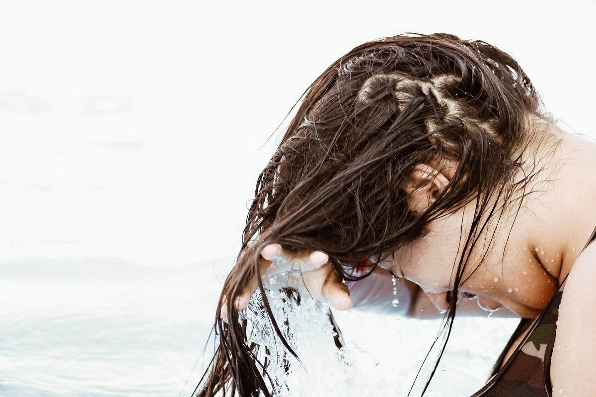 Kobieta spłukuje naturalny szampon z włosów