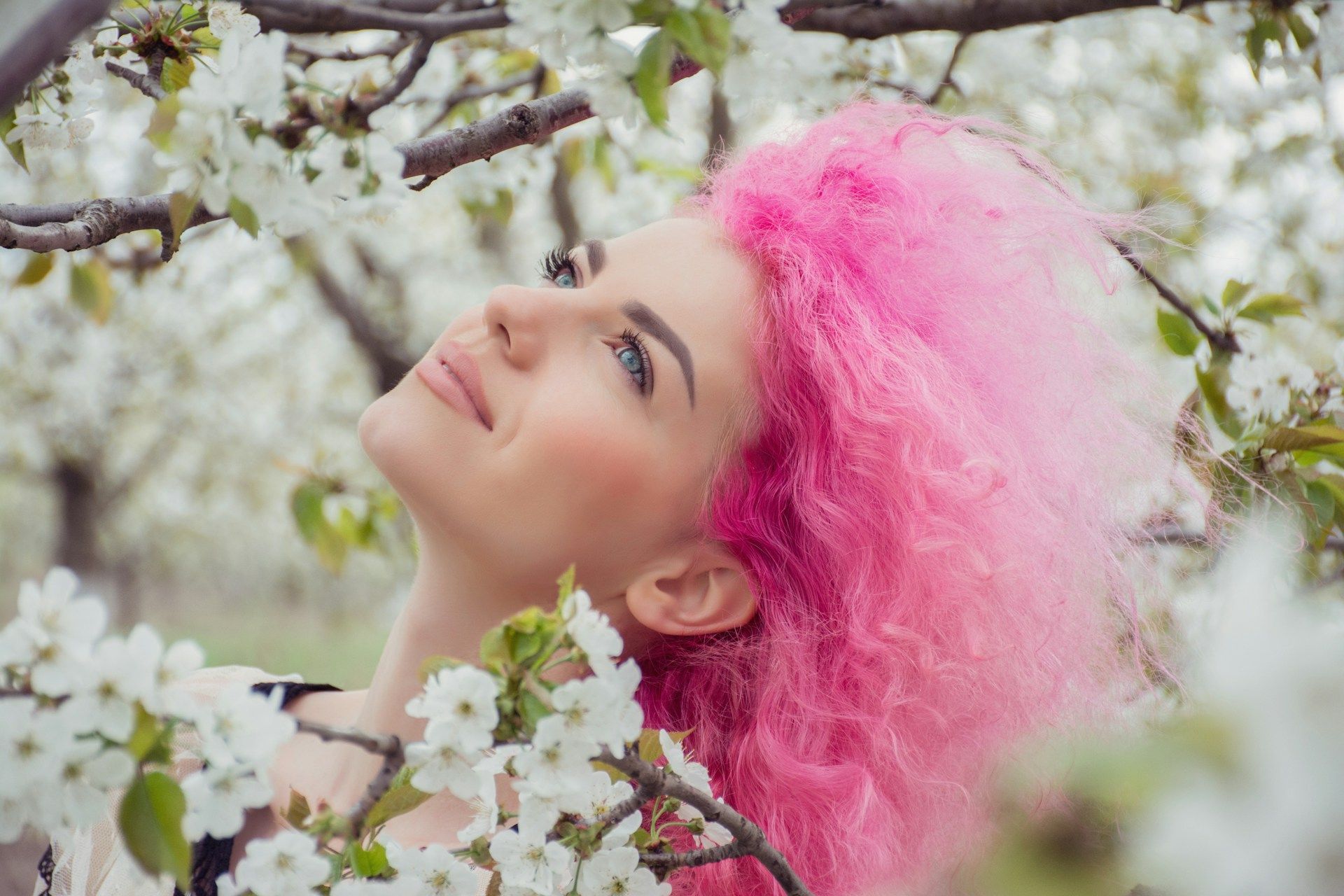 Dziewczyna z różowymi włosami na tle kwitnącego drzewa