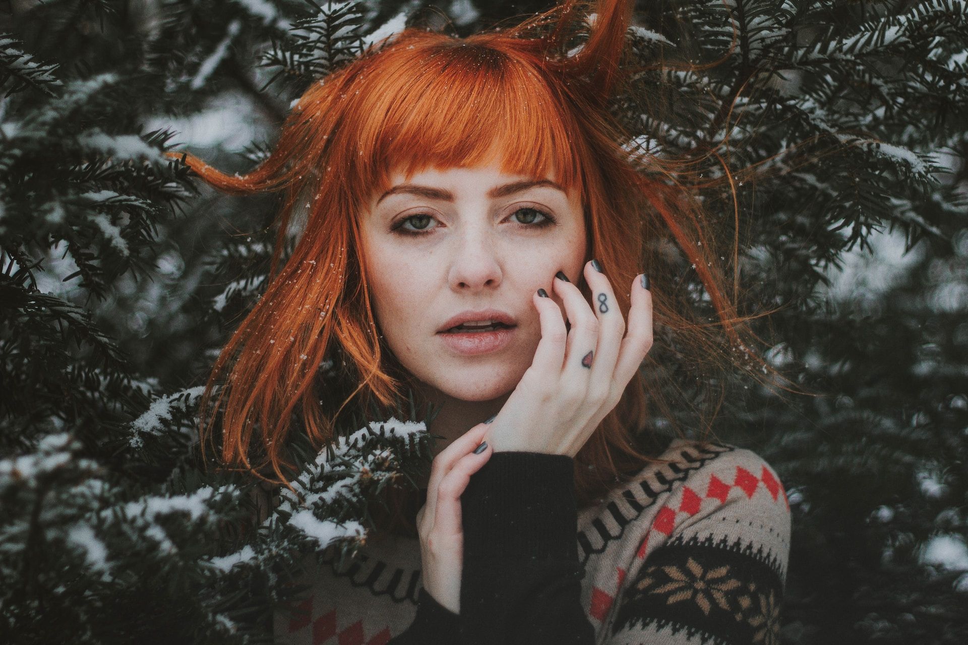Dziewczyna o rudych włosach na tle choinki zimą